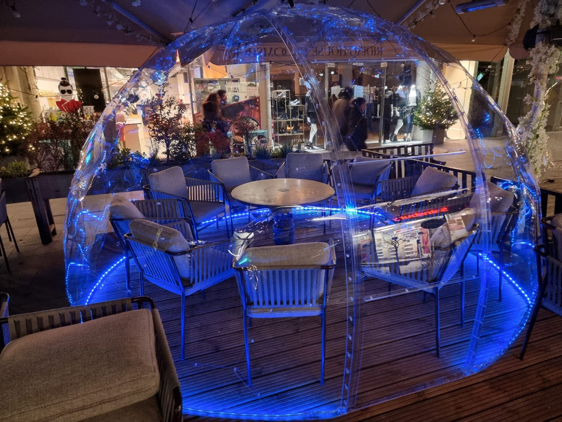 Diners inside a GeoDomeX dome lit in blue on a restaurant terrace