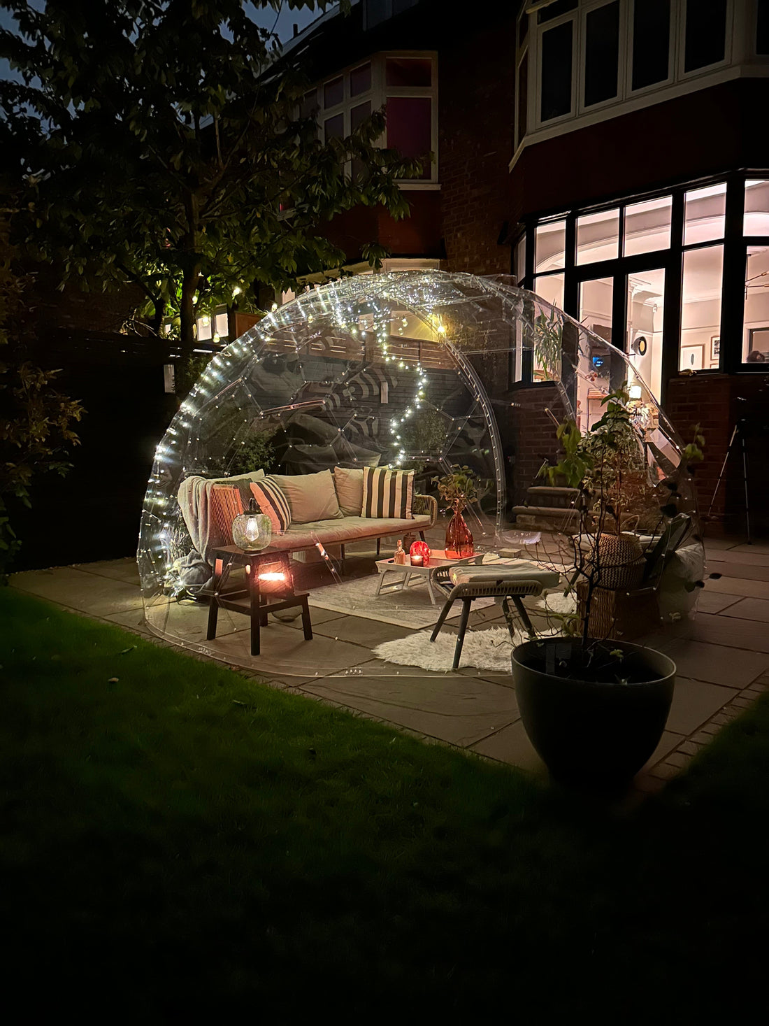 A cosy GeoDomeX lounge lit by lanterns at night