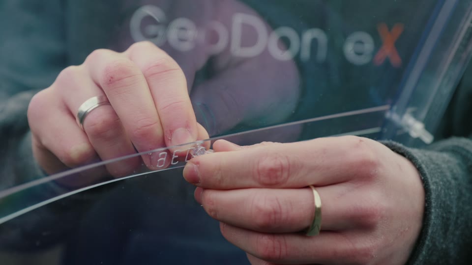 Hands holding an engraved, numbered GeoDomeX panel